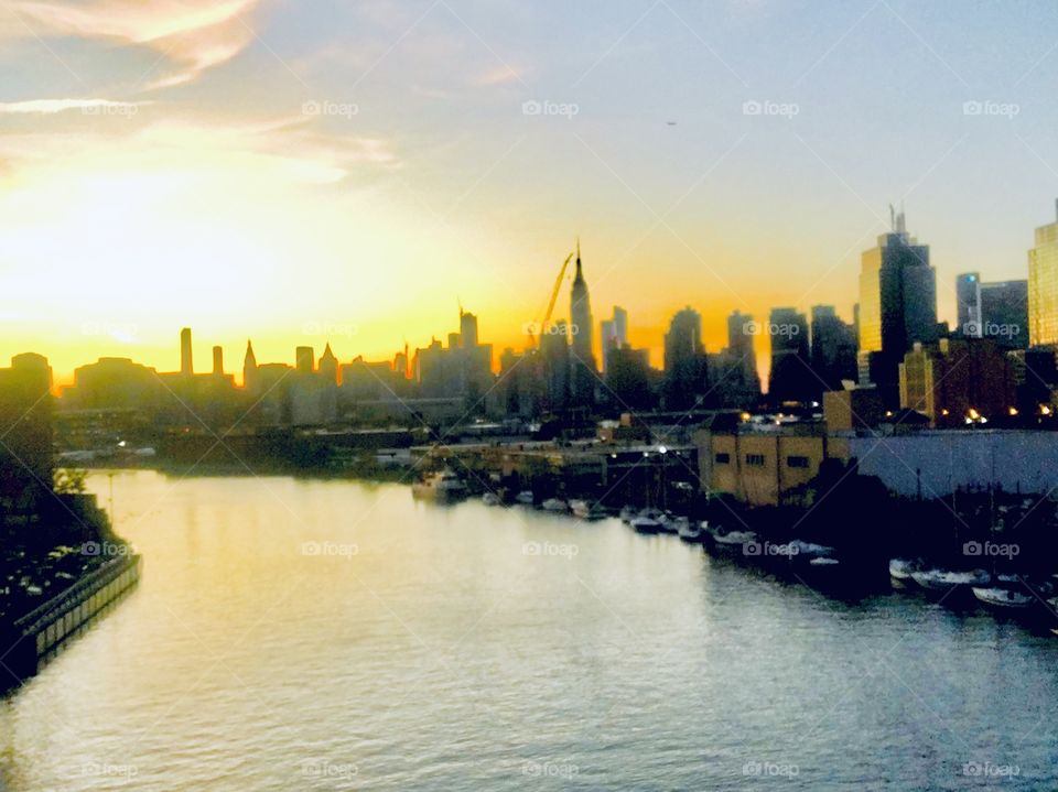 A picture of the golden light of the sunset against the misty gray sky and the silvery gray waves of the East River at Newtown Creek in Long Island City, Queens, New York taken in 2018, Hypnotic Productions