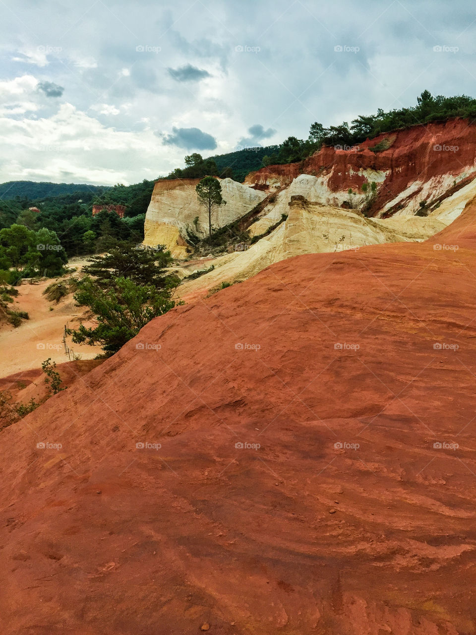 Nature reserve called Colorado Provencal in France witt trees and orange colored sand dunes high as mountains a rainy day in summer.