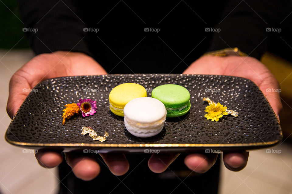 Shapes circles and ellipses with round colorful macaroon biscuits on a black plate.
