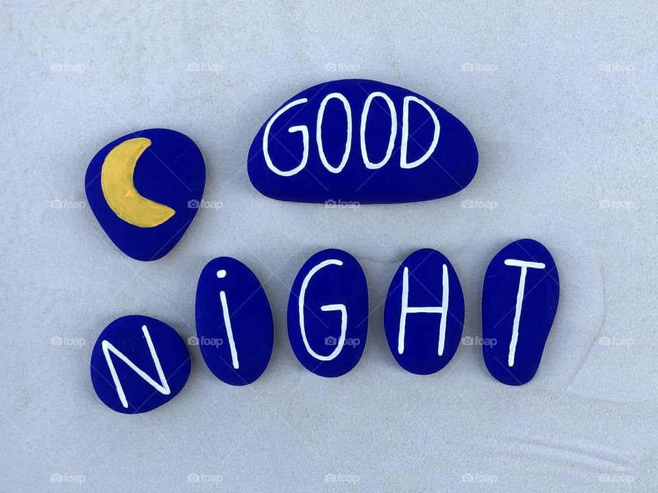 Good Night text with blue colored stones over white sand 