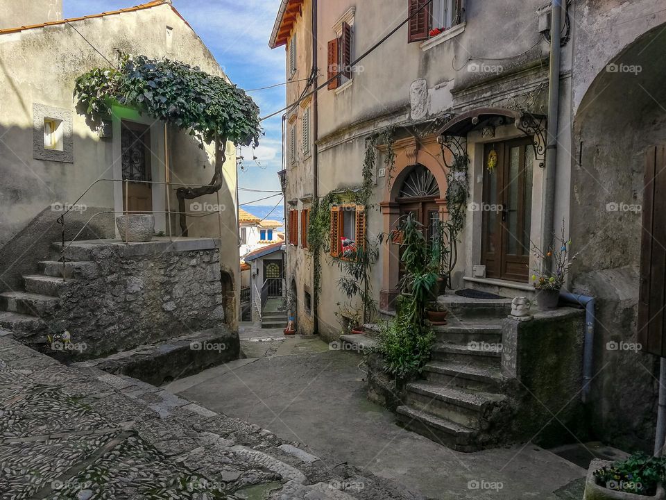 Empty alley in old mediterranean village with stone houses and green plants
