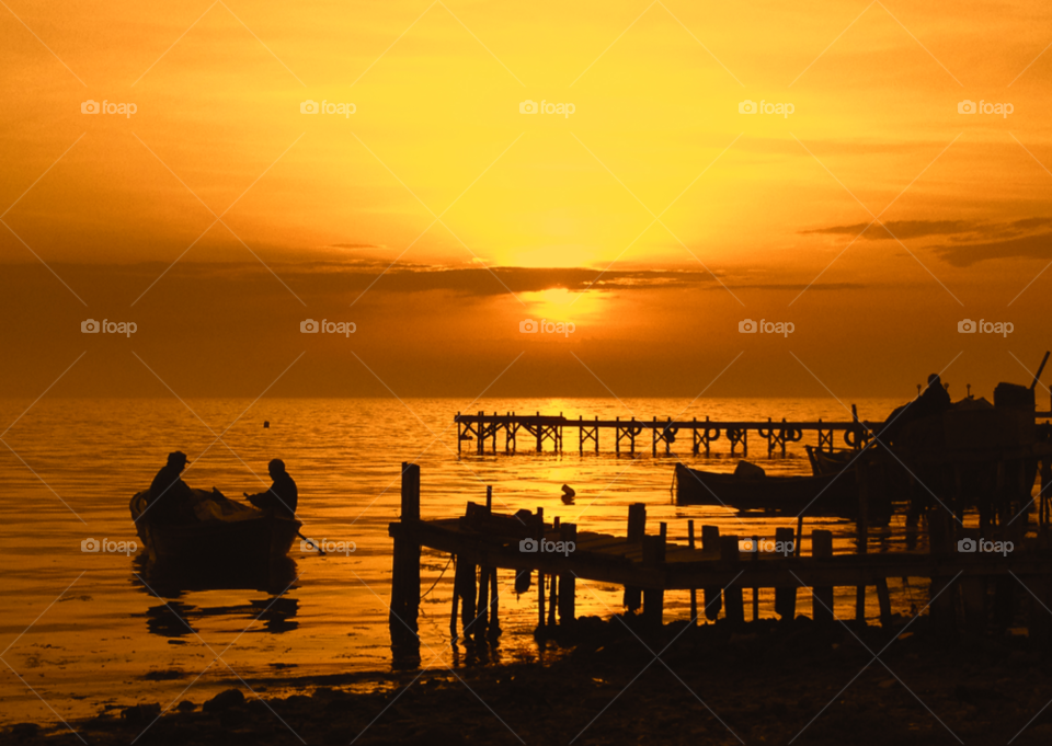 Silhouetted fisherman on boat at sea