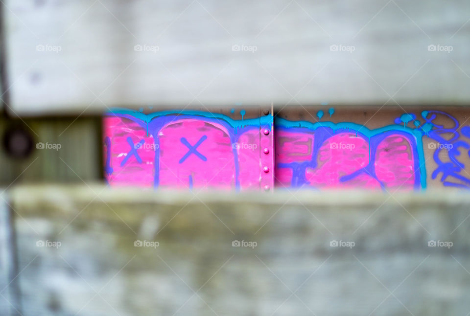 Pink graffiti letters beyond a wooden fence