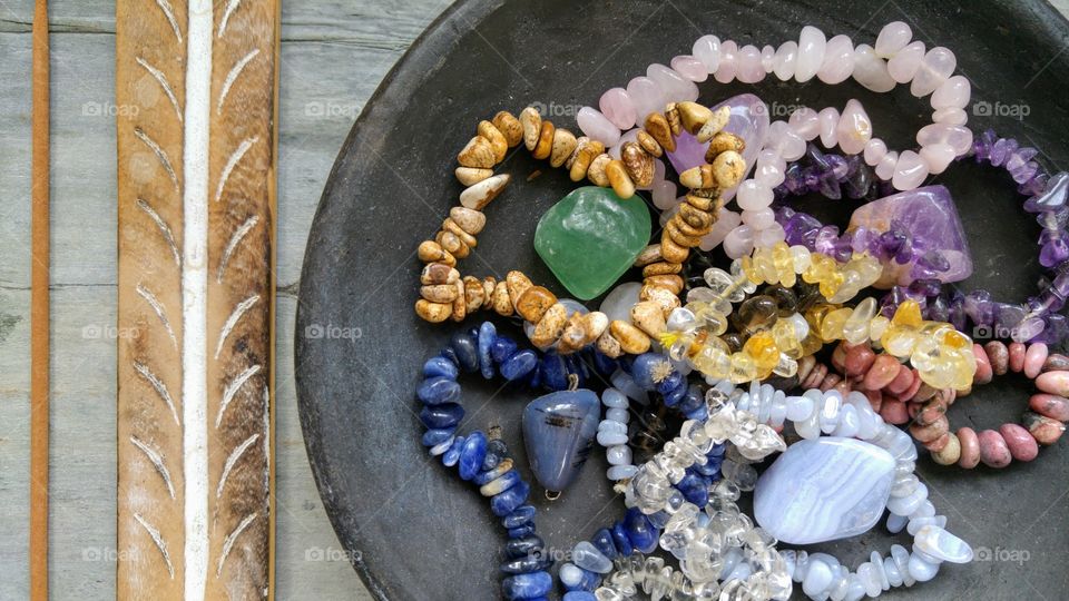 black bowl with gem stones on a grey wooden background with incense