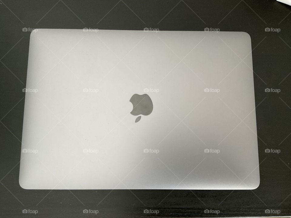 A closed MacBook Pro on desk looking straight up at the camera 