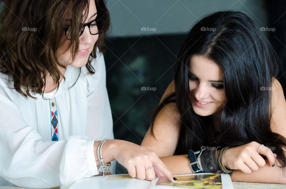 Two smiling looking in magazine