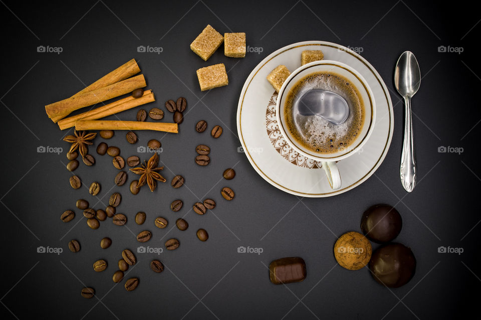 coffee still life on a black background is a mug with a coffee a plate with a cake and sweets with brown sugar