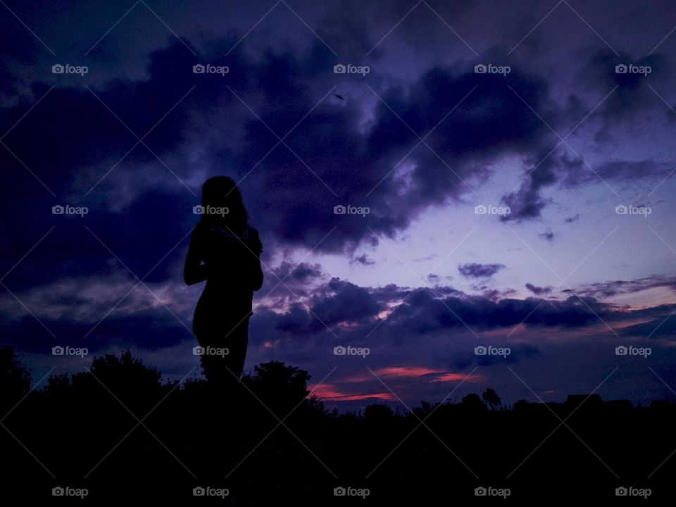 Girl silhouette on sunset background