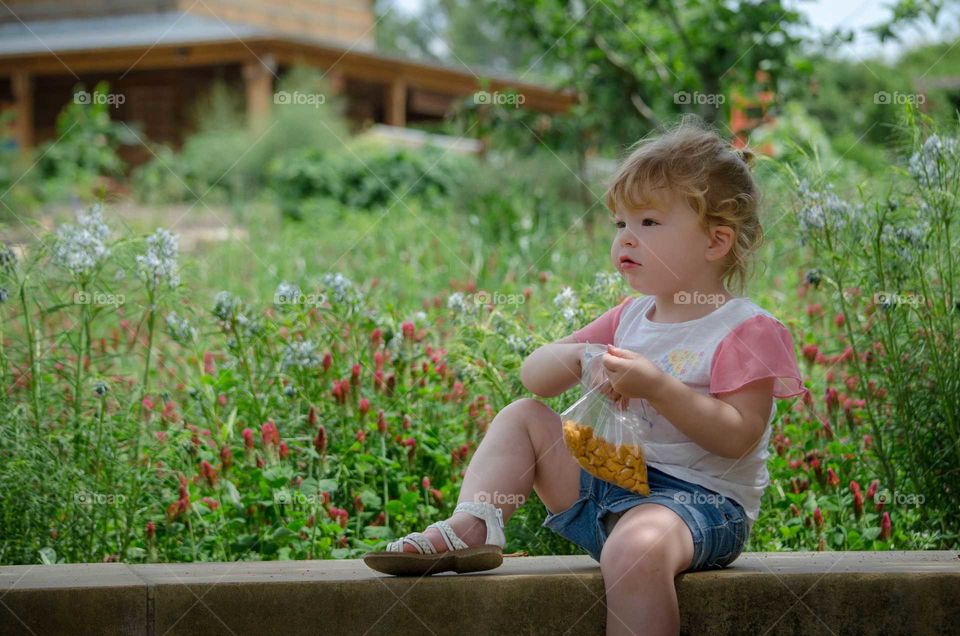 Cute girl sitting on wall eating food