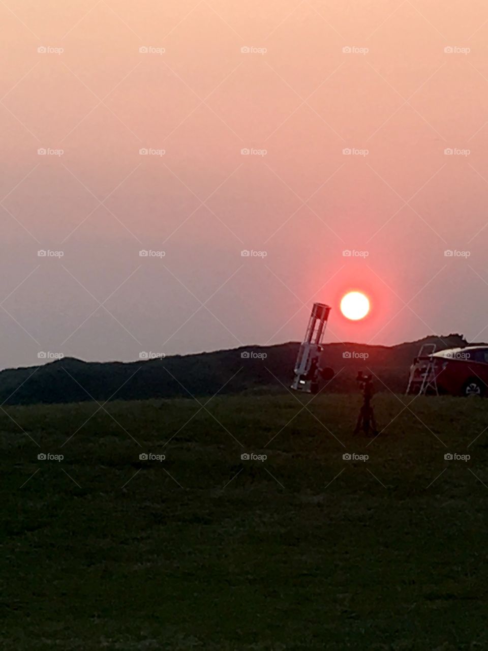 Large telescope on a hill at sunset. Star gazers waiting for the stars to come out.