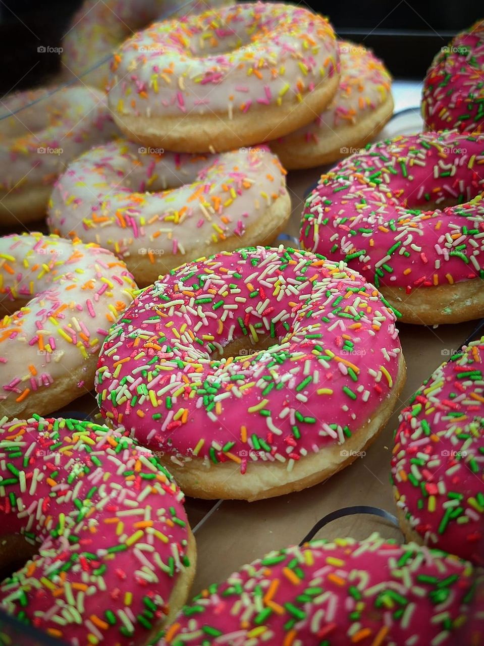 Food.  Dessert.  Rows of colorful donuts. Side view