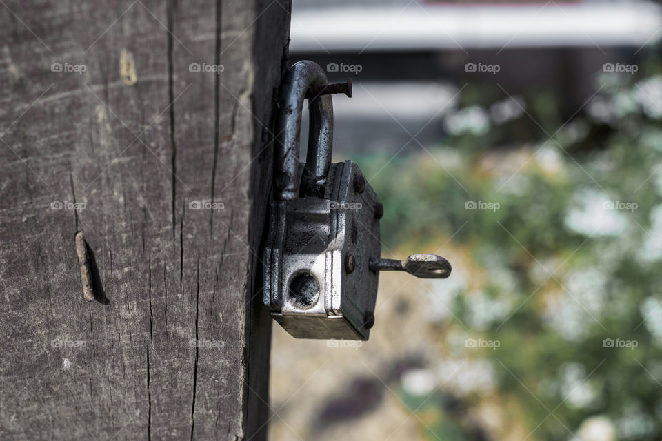 An old iron padlock hanging on a wooden plank