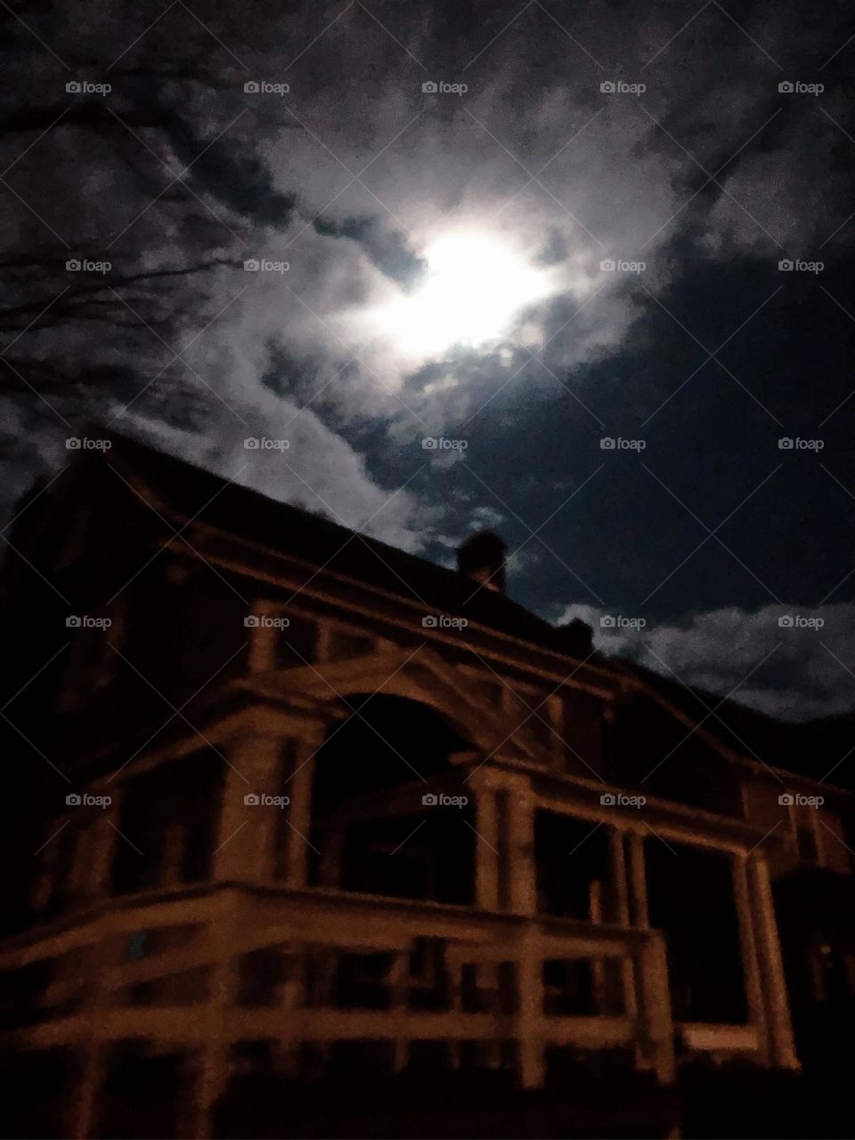 This night time picture of the burst of light is the moon and the structure of the house is brilliant in the dark shades 