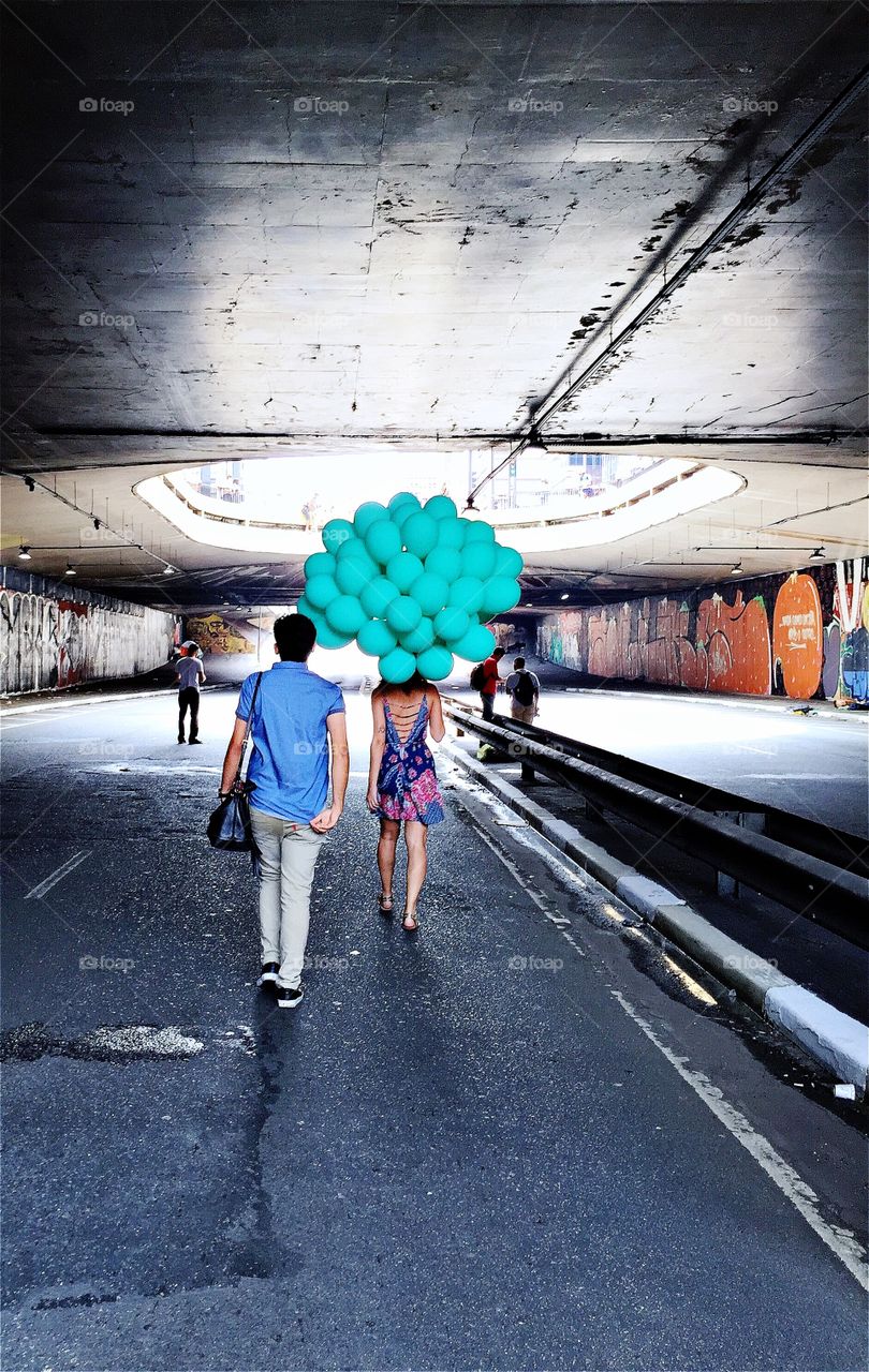 Couple with balloons walking in a tunnel