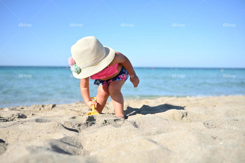 little girl in a hat playing with sand
