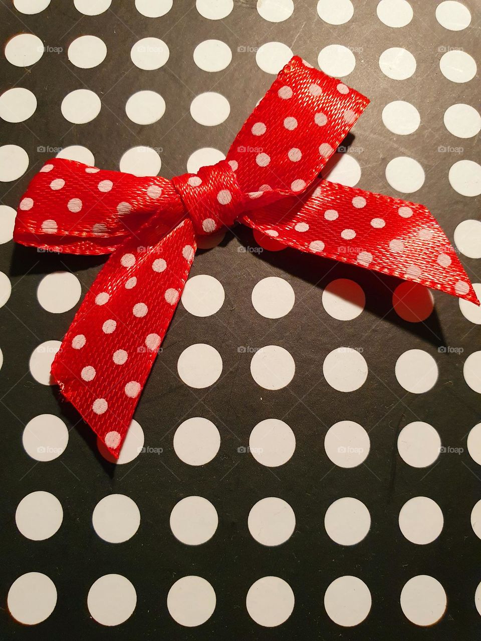 red bow with white dots on black paper with white dots