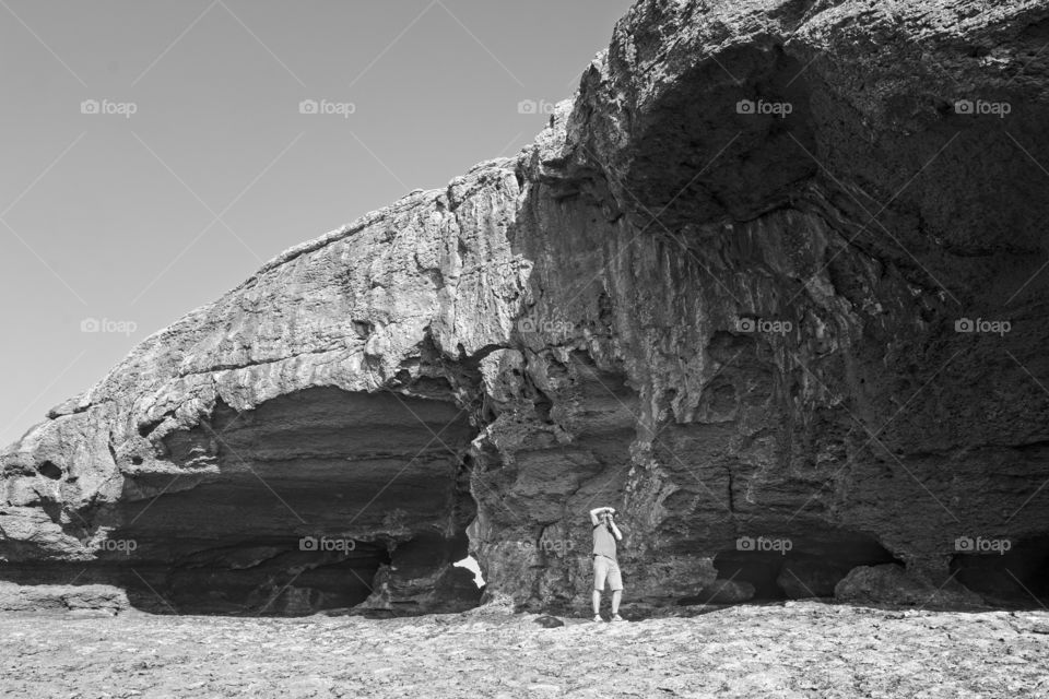 Man taking a photo in front of a cliff