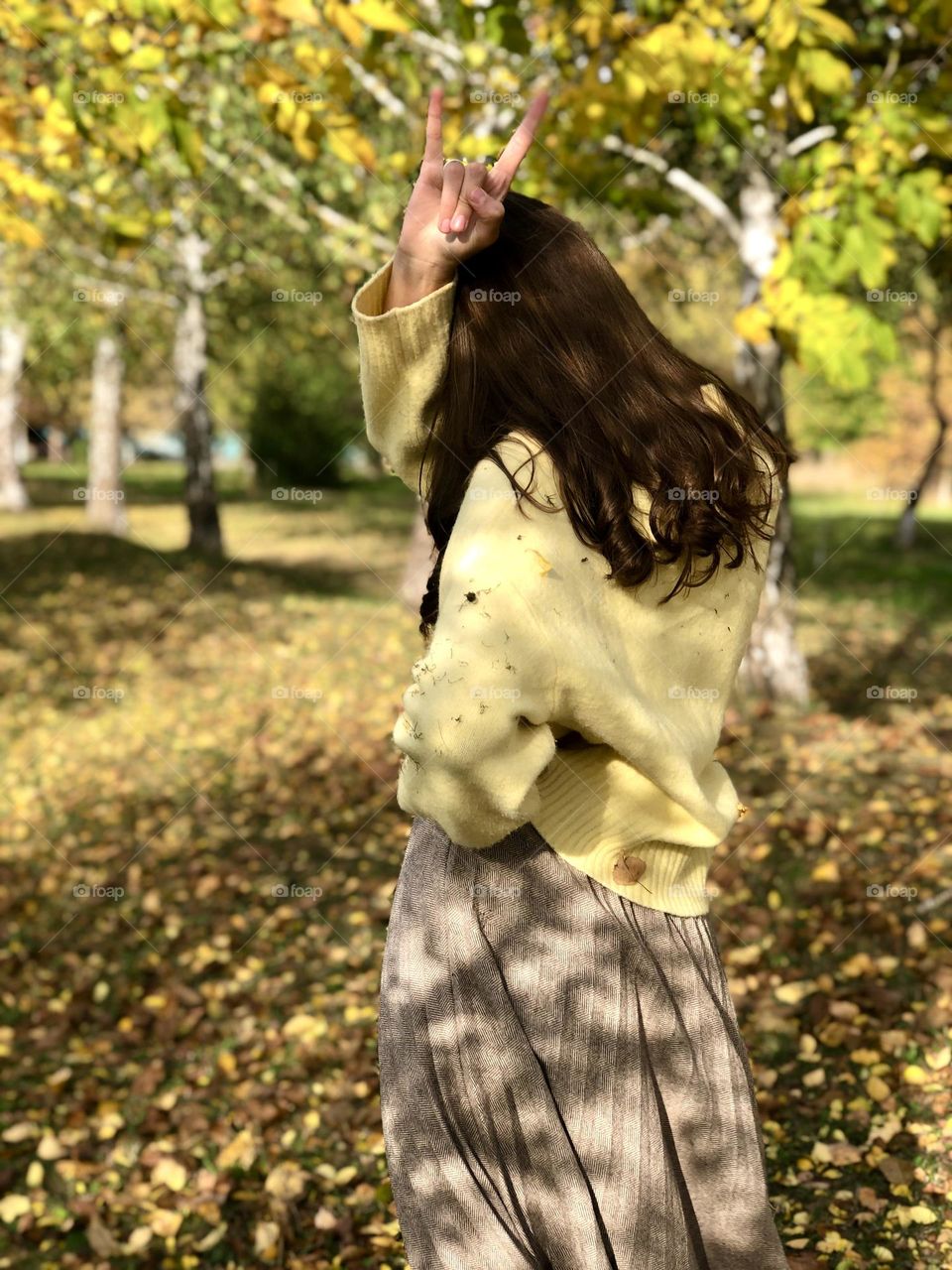 Girl standing back to camera and showing a hand gesture “Cool”