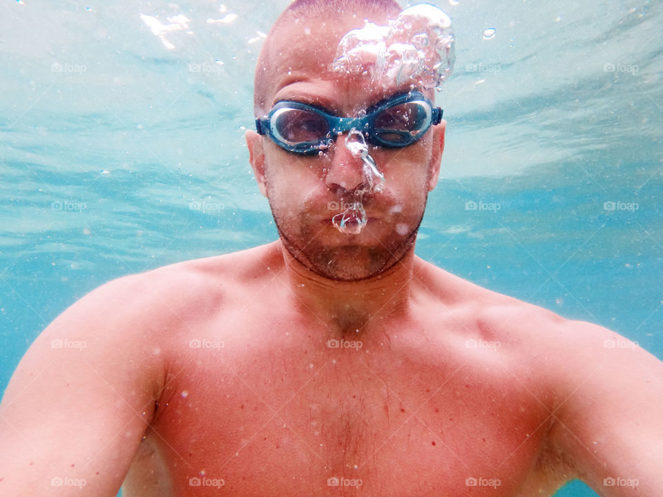 man with goggles underwater. man with goggles underwater making bubbles