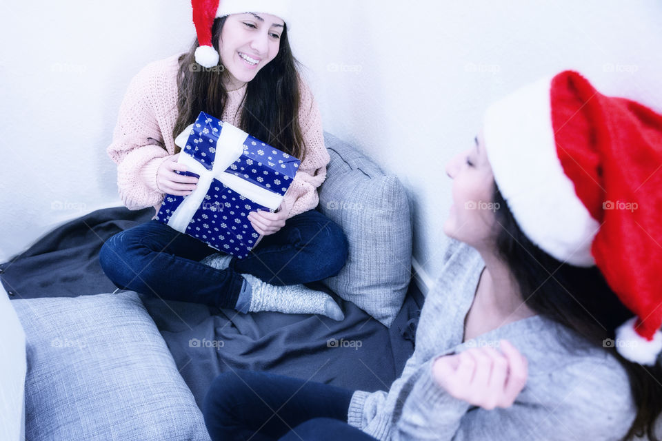 Two girls giving Christmas presents to each other 
