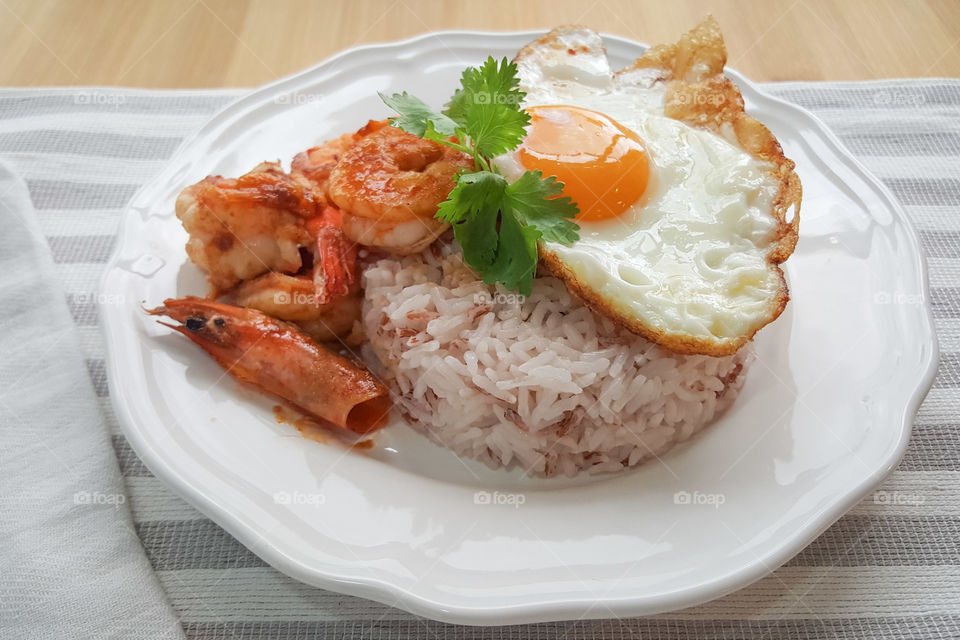 Thai cuisine : Shrimp fried with garlic pepper. Serve with cooked jasmine rice and Fried egg adding coriander leaves on top.