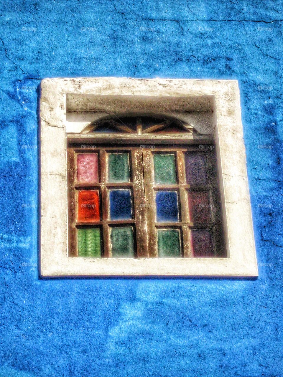her image blue painted cement wall with colorful old stained glass window
