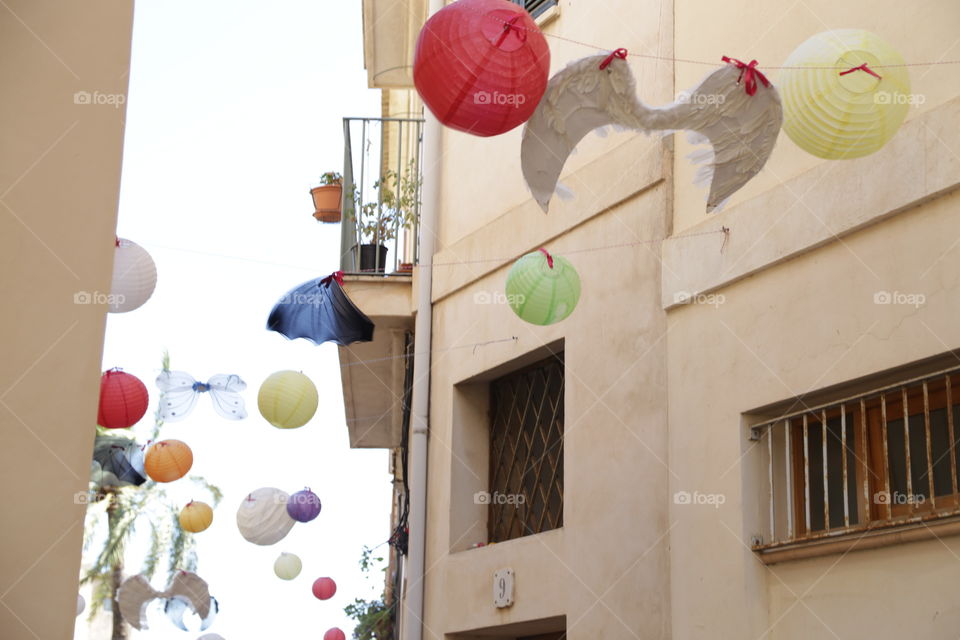 Round festival ornaments hanging outdoors in between the houses against the sky somewhere in Spain 