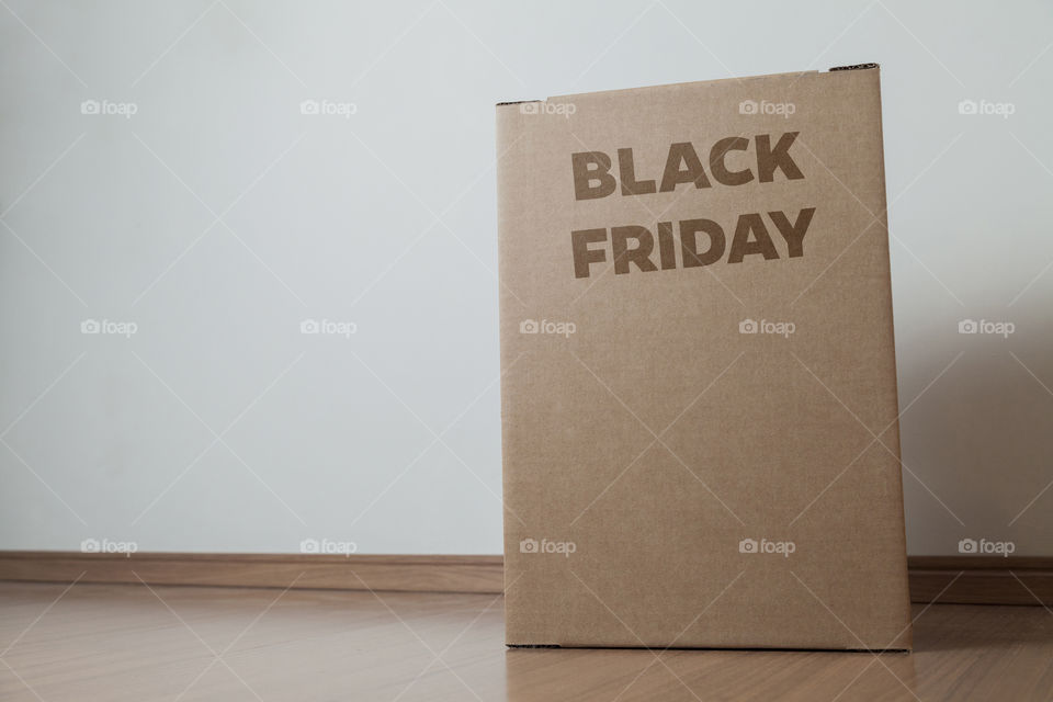 Cardboard box with black friday order written on the box placed on the floor in an empty room with a neutral background. delivery concept. economy concept. black friday concept. shopping concept.