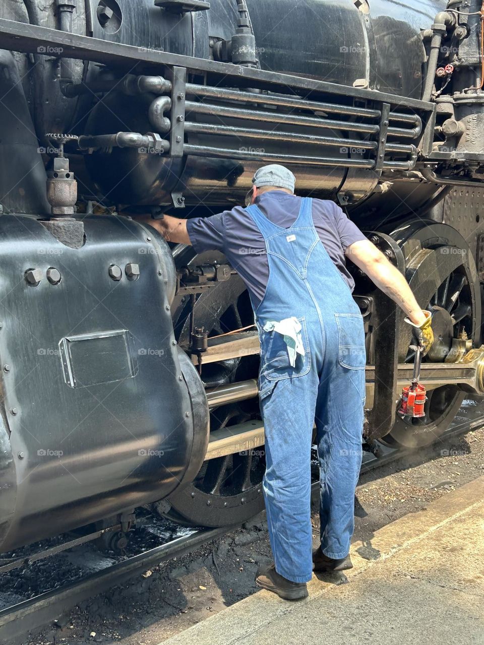 Train engineer oiling brakes on steam engine train 