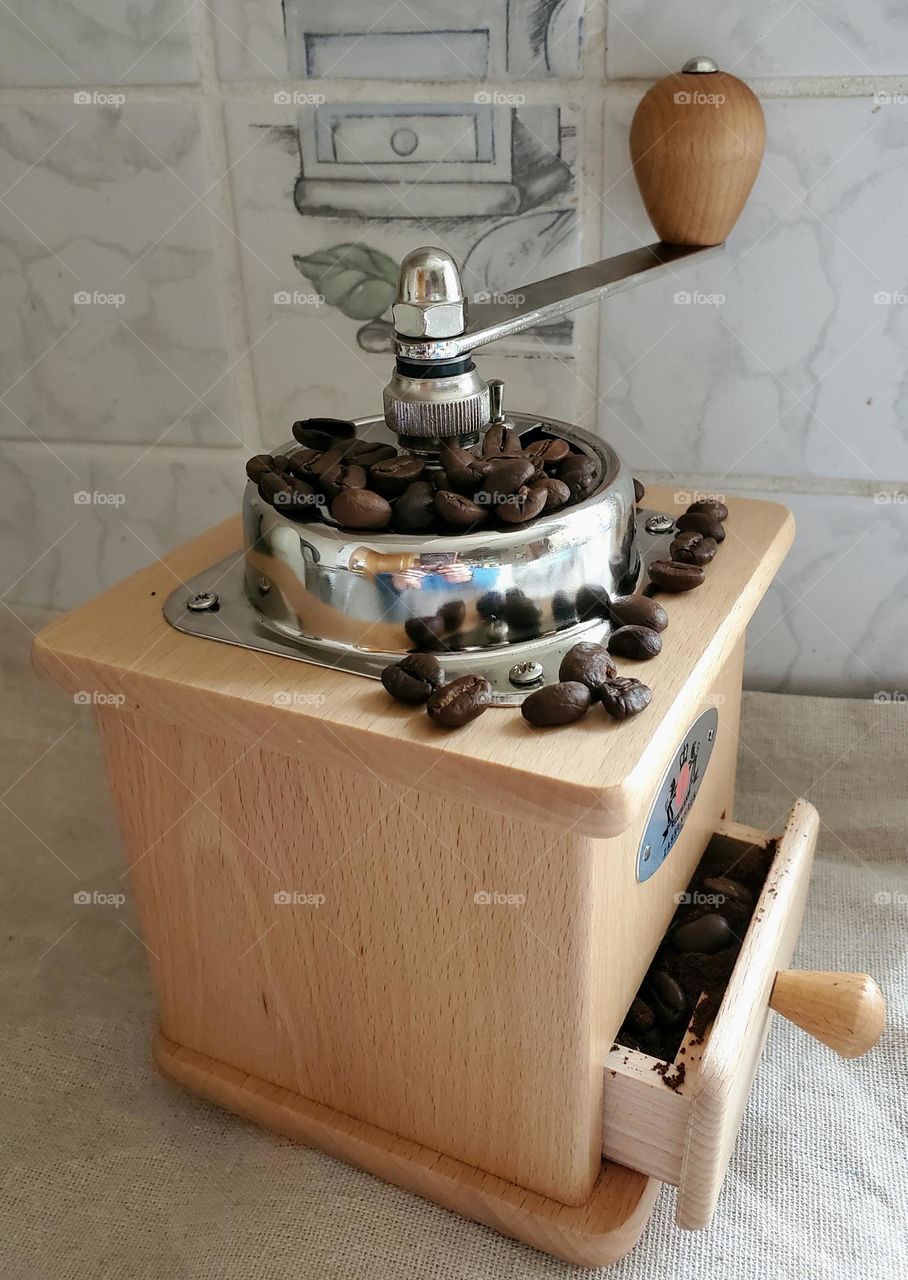 Hand made freshly grinded coffee beans with a wooden coffee mill.