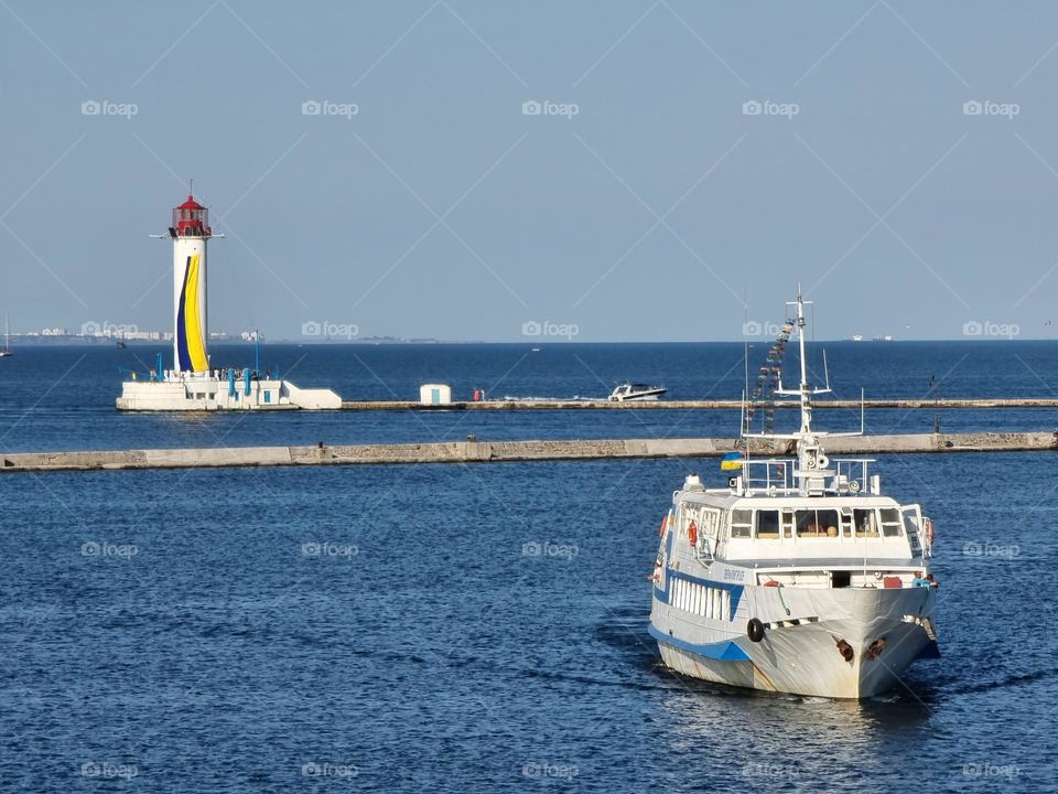 Boat and lighthouse decorated in Ukrainian colors in the port of Odessa, Ukraine at the Black Sea on a sunny day