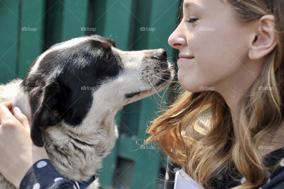 Bond of love between humans and our dogs. Young girl and border collie, having a smooch, candid moment, profile view, authentic affection.