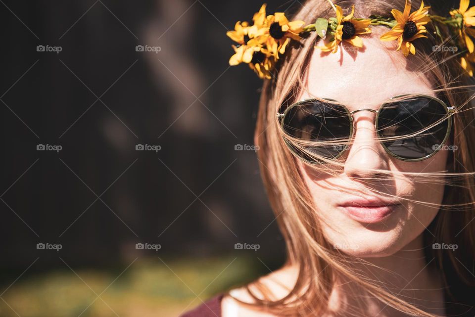 Portrait of a young woman wearing sunglasses and a crown of flowers in her hair 