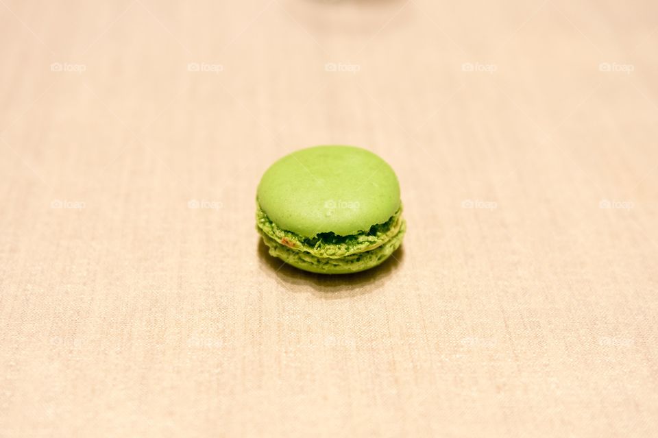 Isolated green macaroon centered on light colored background.