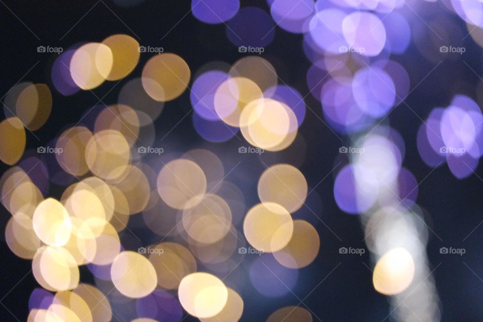 Purple and gold flashy lights mingle as the fireworks they come from light up the sky