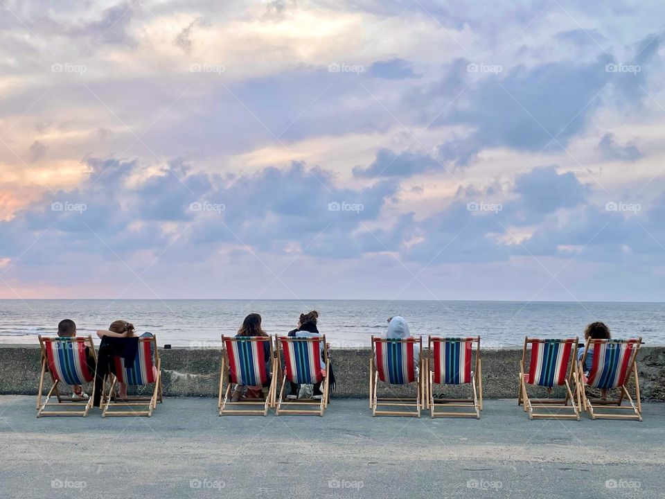 Low angle view of people watching the sunset by sea. 