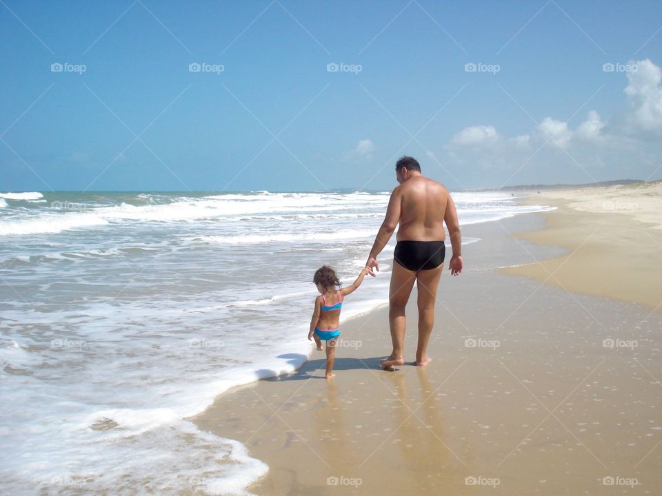 Father and daughter walking on the beach in Jericoacoara, Brazil