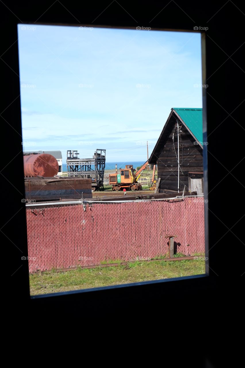 Outside the window of a train, industrial scene near the sea