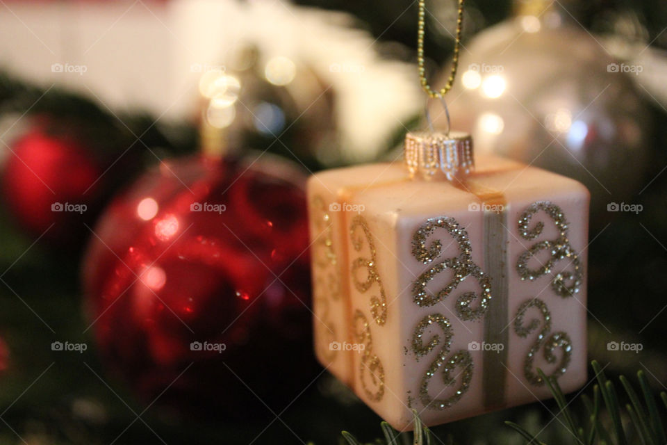 little wrapped Gift and red christmas Balls hanging from christmas tree close-up