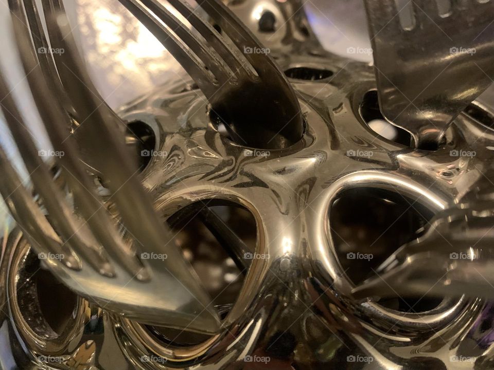 Forks sticking out of holes in a decorative vase