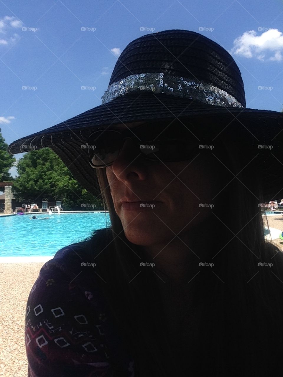 Mystery woman. Woman in a hat by the pool