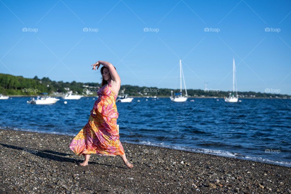 Dancing by the water, swinging dress in the wind, creative mind flowing by the water while the boats rock on the water. 