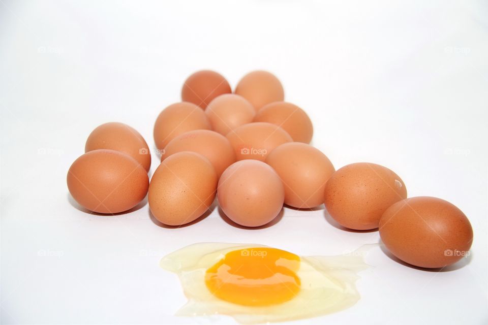 Brown egg with fried egg over white background