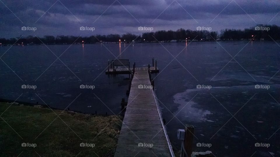 Lonely pier at dusk in frozen Lake