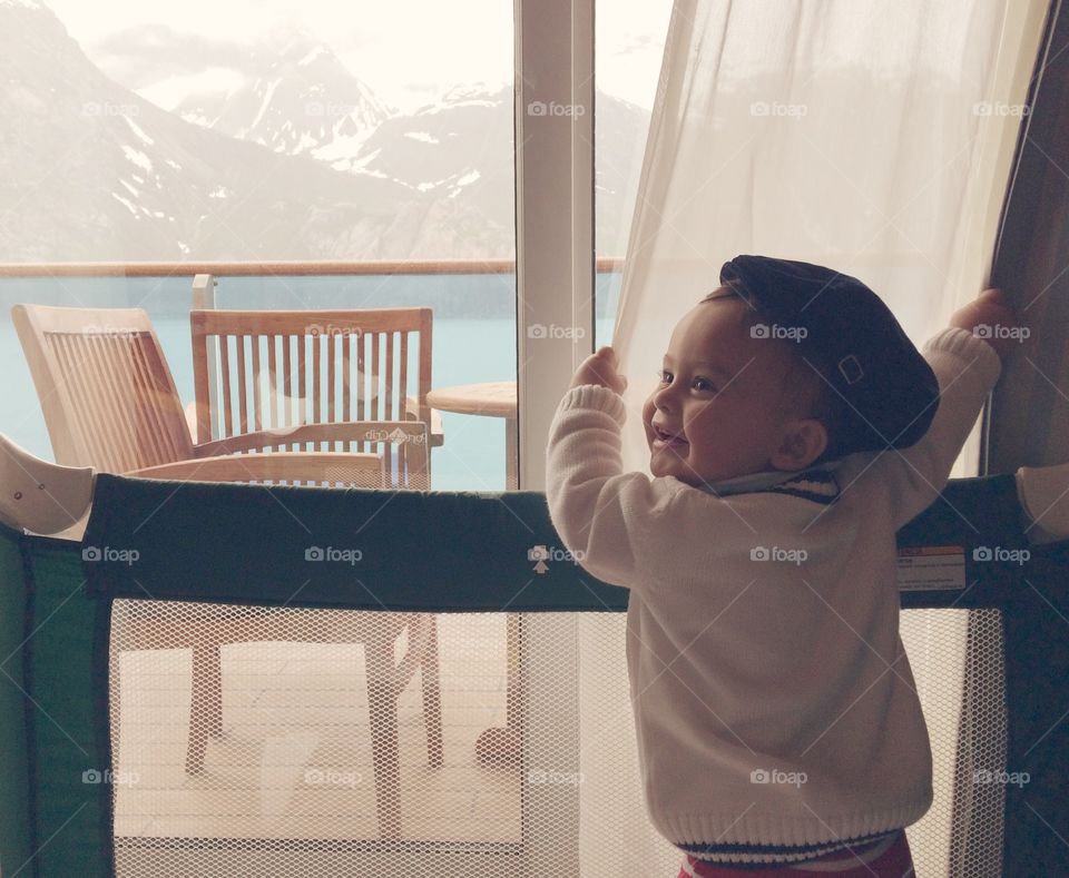 Cute boy holding curtain of window against mountain