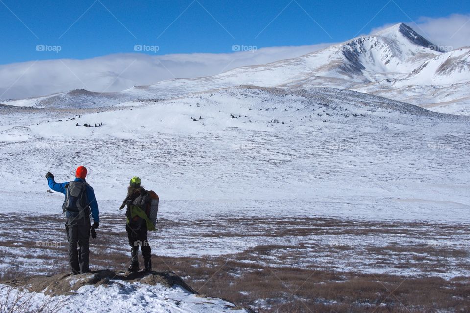 men look out over a valley on a winter mountaineering journey