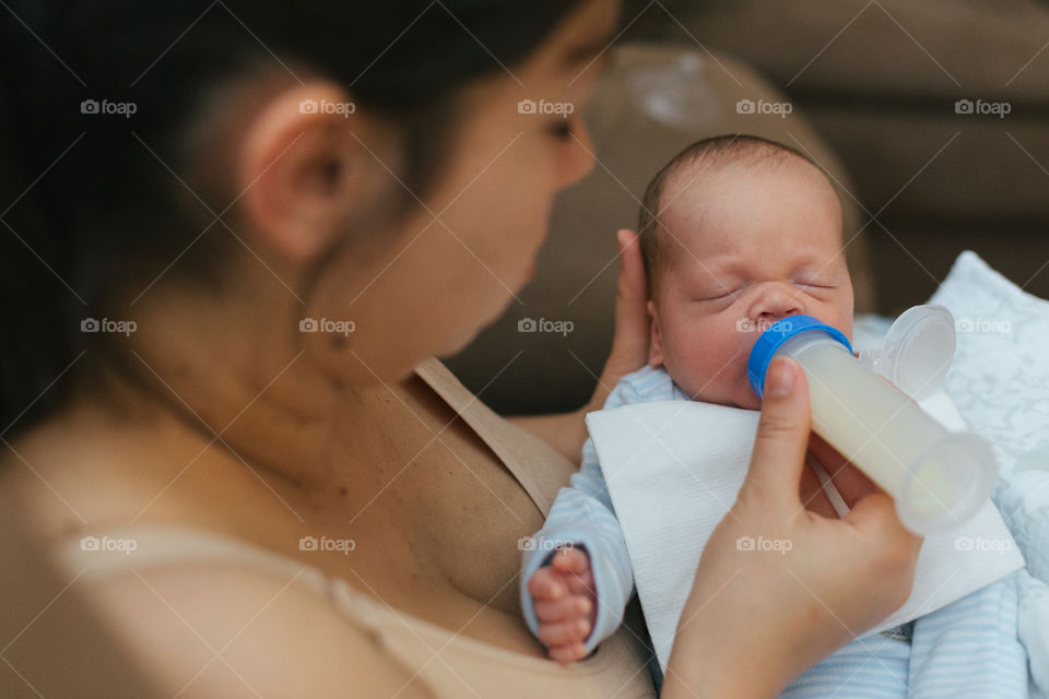 Mom feeding newborn baby from bottle 