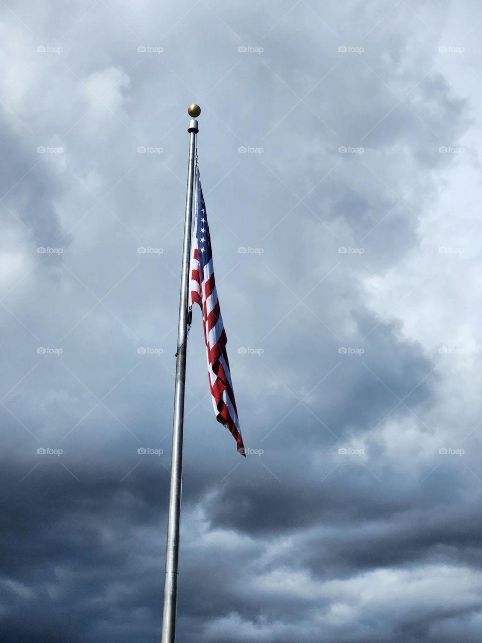 American flag against gray cloud sky