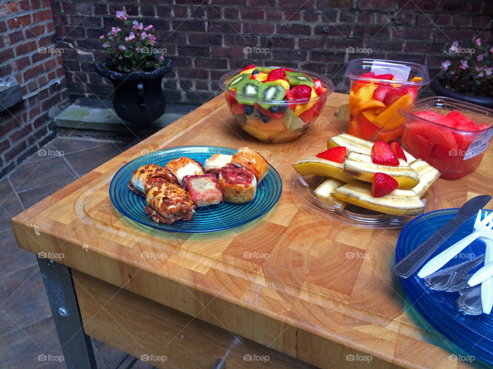 Fresh summer salads made from berries and fruit and pastry outdoors on wood table on patio ready to be served for a healthy breakfast or brunch 