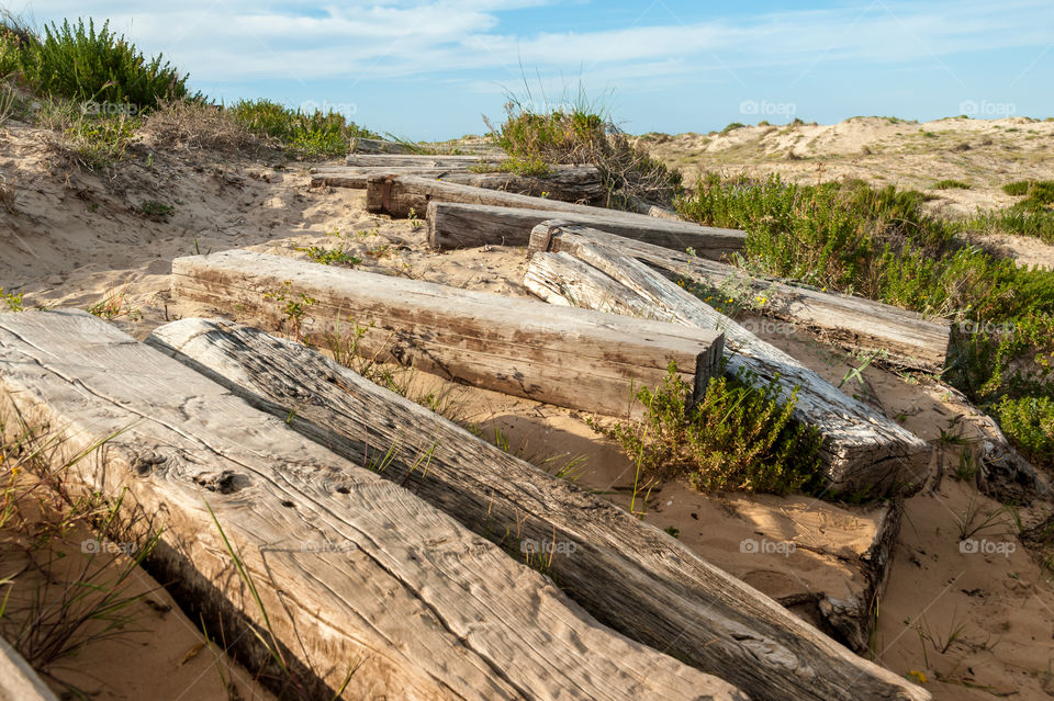 Derelict railway sleepers footpath on coastal sand dunes.